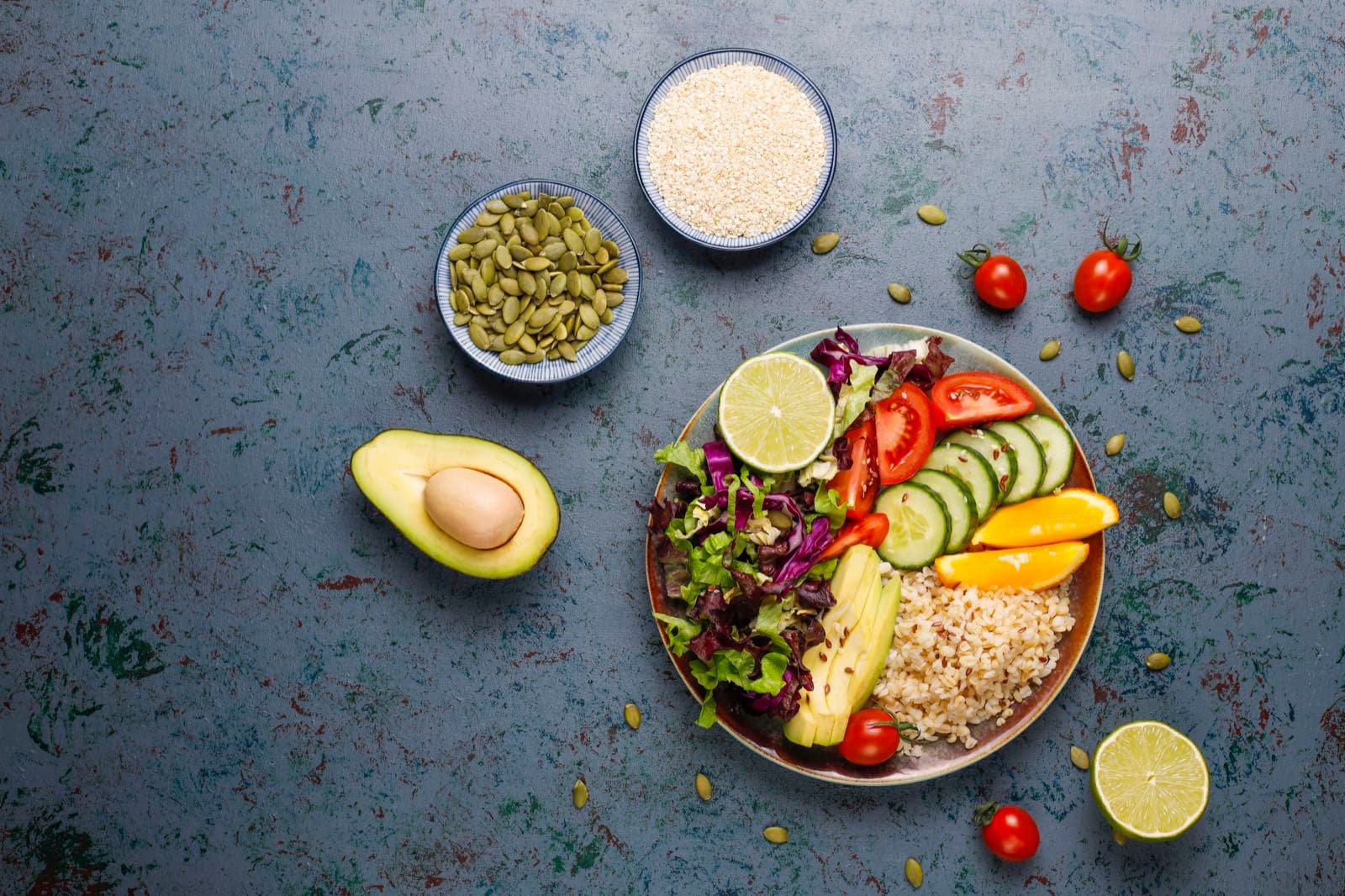 Vista cenital de un plato con ensalada, arroz, pepino, aguacate y naranja