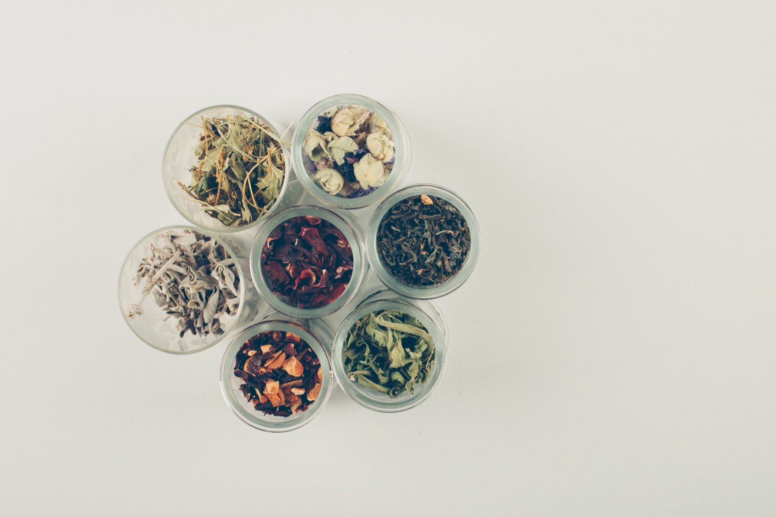 Frascos pequeños con distintas hierbas secas y flores para té