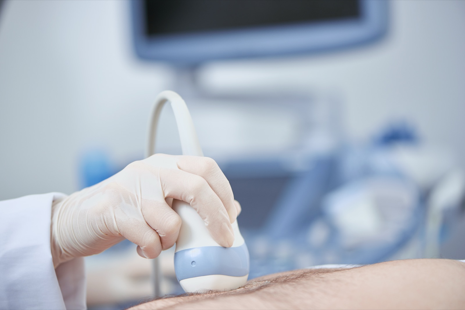 Transductor de ultrasonido sobre el abdomen, con el equipo al fondo